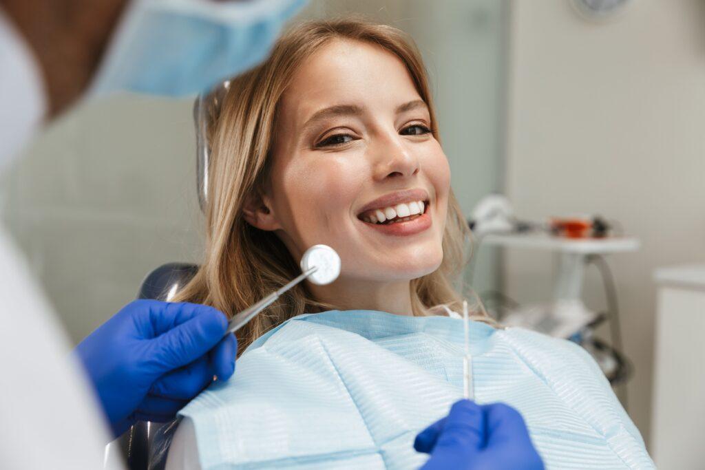 Bild einer schönen Frau, die im Zahnarztstuhl sitzt, während ein professioneller Arzt ihre Zähne repariert