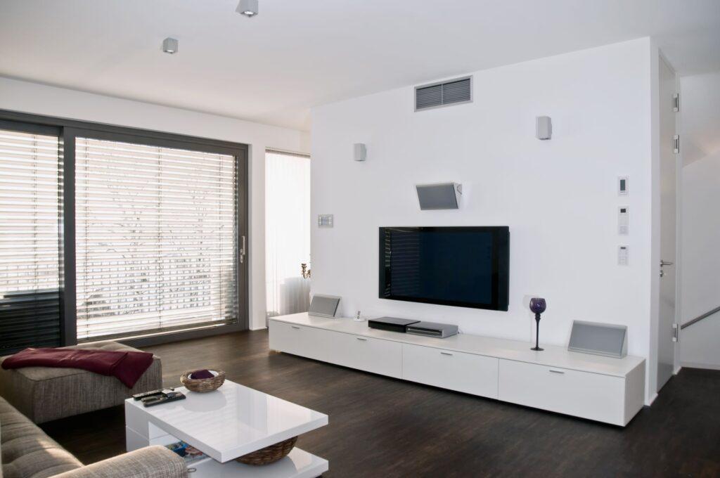 Modernes Wohnzimmer mit elegantem weißen TV Lowboard, großem Flachbildfernseher und stilvollem, minimalistischen Design für ein aufgeräumtes und harmonisches Ambiente.