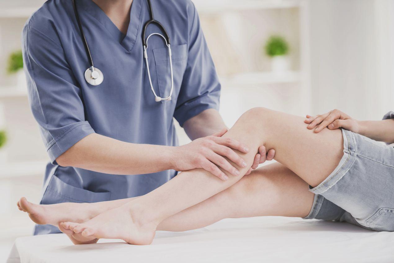 Orthopäde Köln untersucht Patientin am Knie zur Diagnose von Gelenkschmerzen und Fehlbelastungen