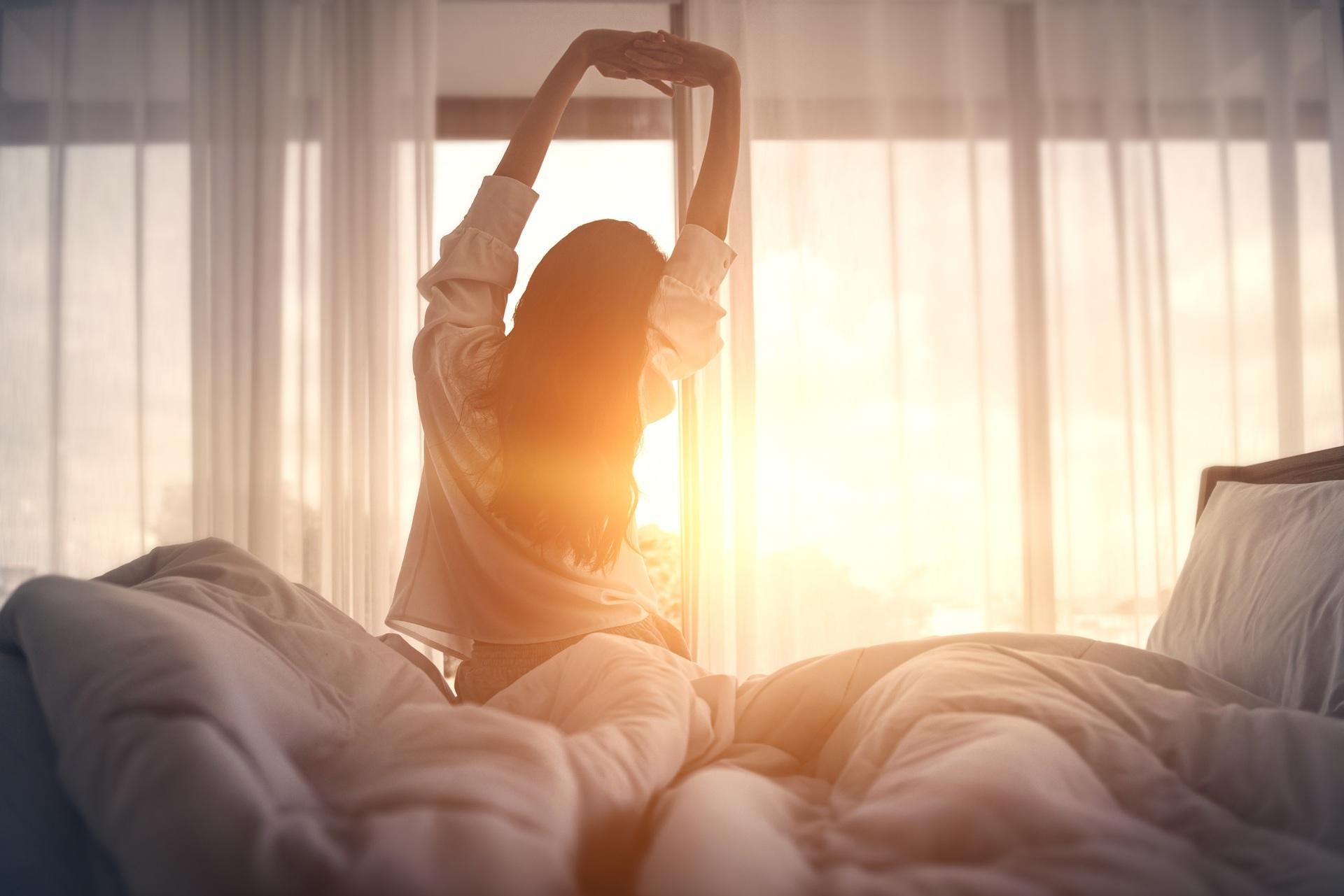 Frau streckt sich morgens im Bett | Primavera Öle